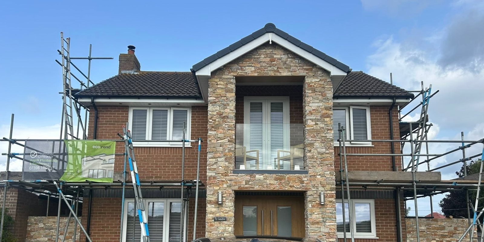 The same house before, bare brick with scaffolding up